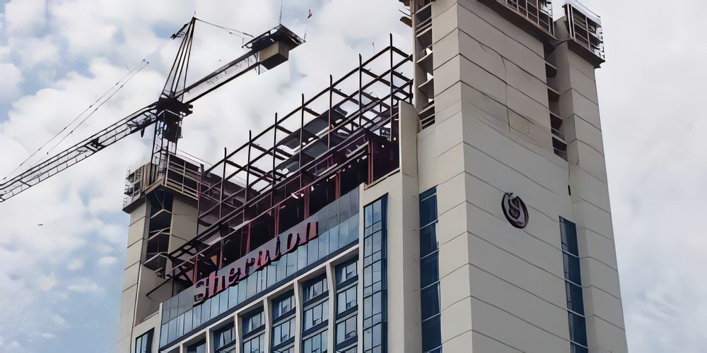 Structural steel topping out a hotel tower, the tower crane still alongside