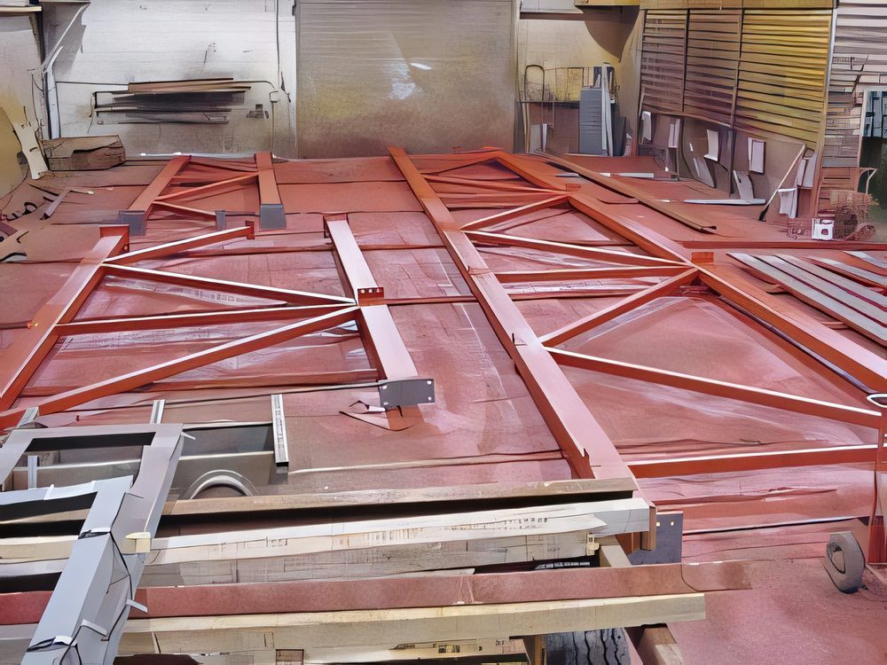 Red-primed steel frames laid out flat in the yard to cure