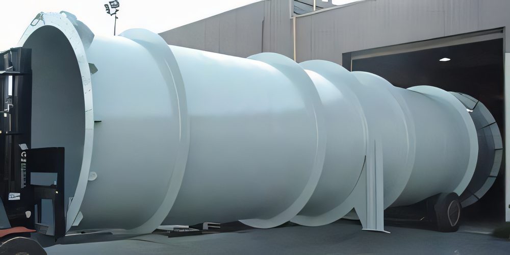 A long white plate duct with flanged rings, carried across the yard by forklift